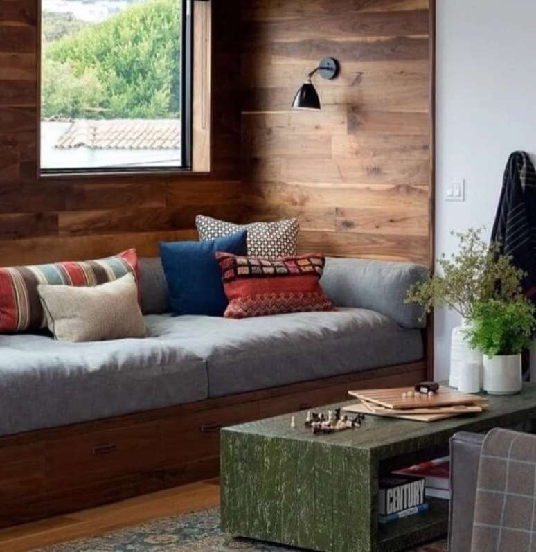 15. O sofá baú de madeira embutido na parede é uma ótima alternativa para espaços pequenos. Fonte: Sinemiss Dekor