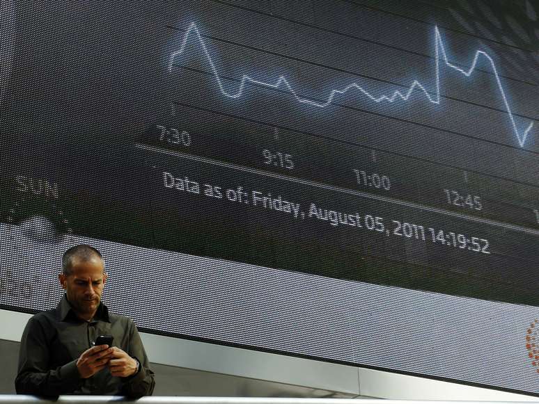 Homem passa por telão com índice FTSE em Londres.   REUTERS/Luke MacGregor 