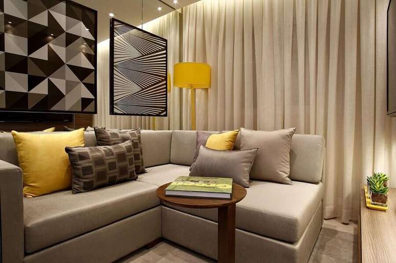 42. Sala bege pequena decorada com detalhes em amarelo e quadros modernos – Foto: Marel
