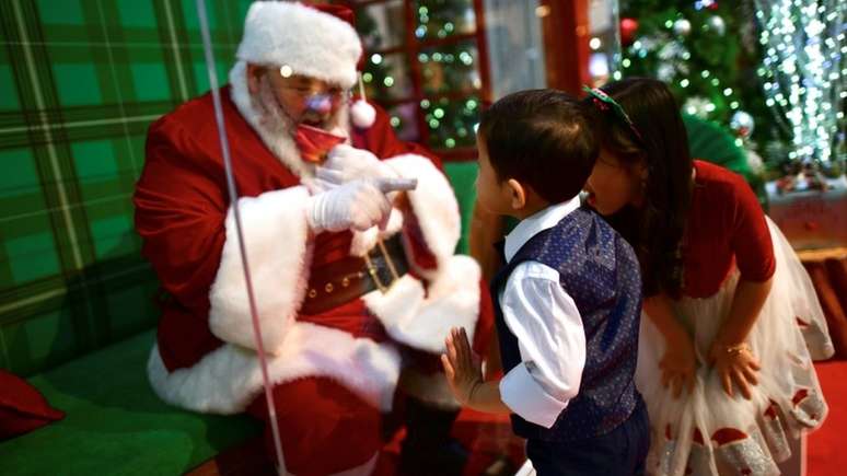 Crianças falando com Papai Noel através de vidro