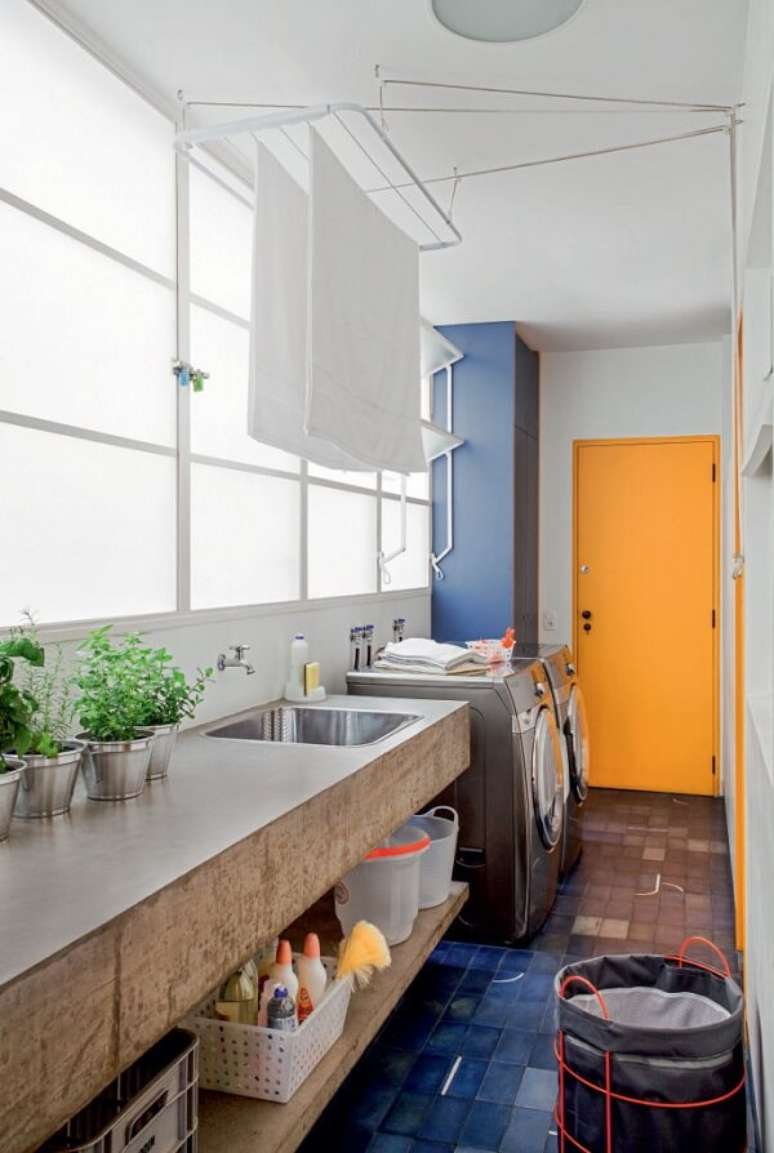 9. A bancada de cimento, os armários azuis, e a porta amarela deixaram a área de serviço simples muito divertida. Fonte: Pinterest