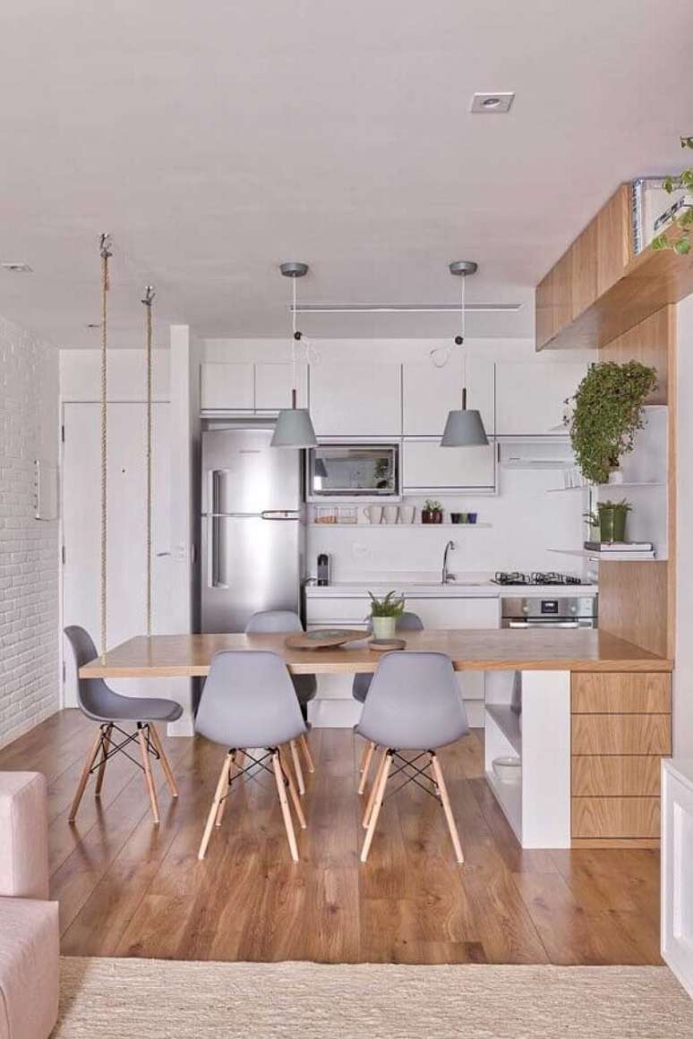 18. Decoração clean com mesa de madeira planejada para cozinha e sala de jantar integradas – Foto: VOA Arquitetura
