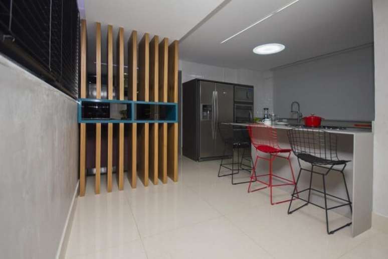 24. A banqueta alta vermelha se destaca entre os assentos em tom cinza. Projeto por Marco Dias Reis