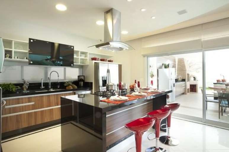 26. A banqueta vermelha preenche o espa&ccedil;o da cozinha com ilha. Projeto por Aquiles Nicolas K&iacute;laris