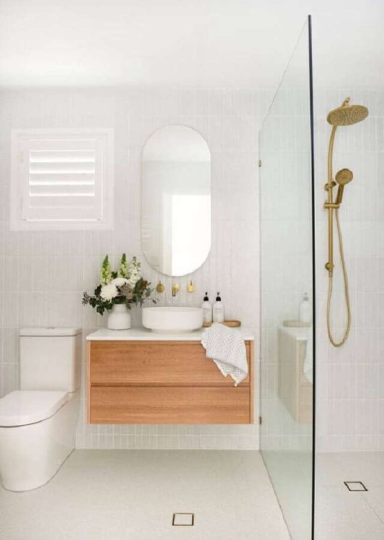 2. Banheiro minimalista branco decorado com espelho oval e gabinete de madeira – Foto: Casa de Valentina