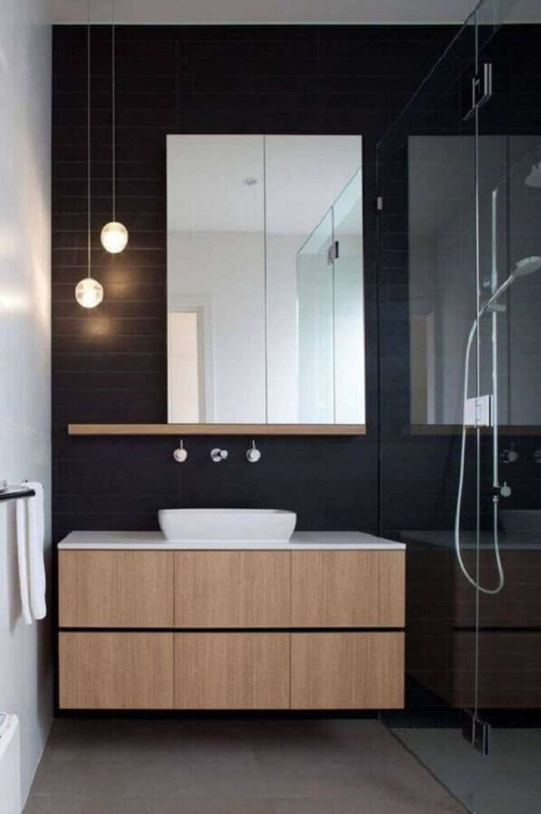 16. Banheiro minimalista preto decorado com gabinete de madeira e espelho sem moldura – Foto: Jeito de Casa