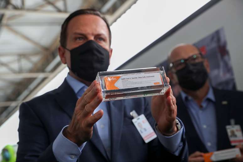 Doria e diretor do Butantan, Dimas Covas (ao fundo), com caixa de vacina chinesa CoronaVac no aeroporto internacional de São Paulo, em Guarulhos
 19/11/2020 REUTERS/Amanda Perobelli