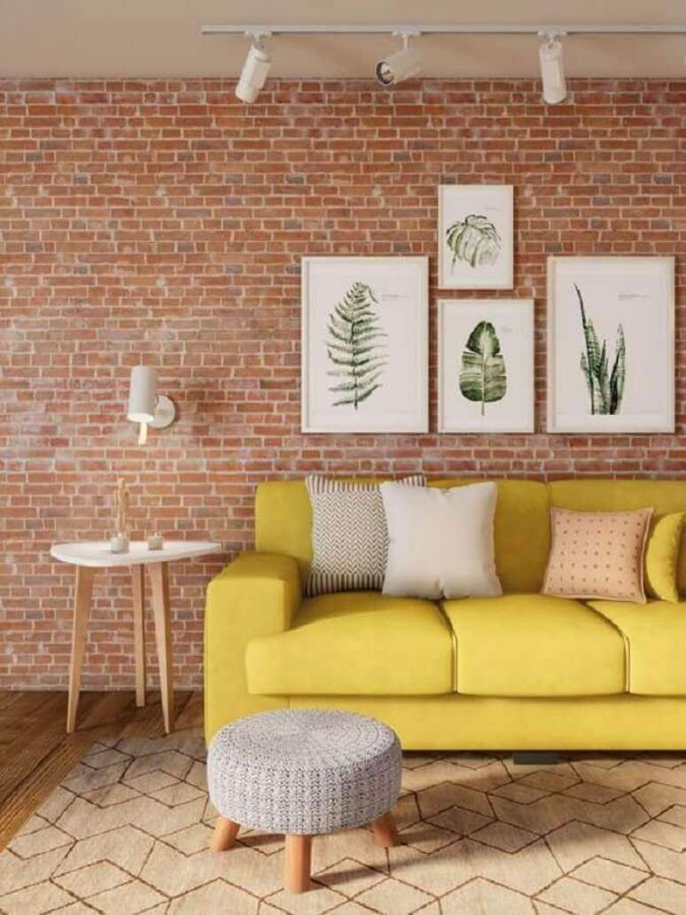 46. Parede de tijolinho com quadros de folhagens para sala decorada com tapete bege geom&eacute;trico e sof&aacute; amarelo &ndash; Foto: Pinterest