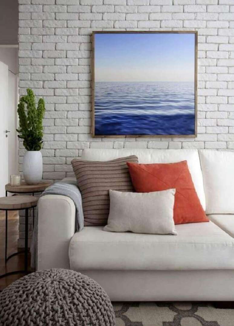 19. Vaso decorativo para sala de estar com quadro azul para parede de tijolinho branca – Foto: Jeito de Casa