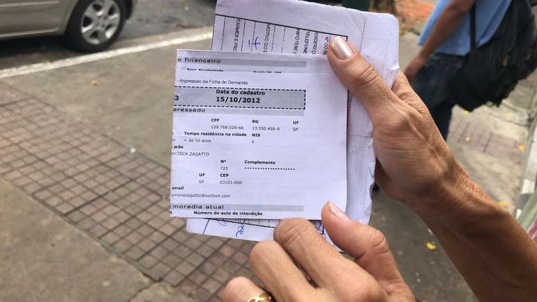 Simone Cabral mostra documento de seu cadastro na fila da moradia da prefeitura. Desde 2012 ela espera ser contemplada