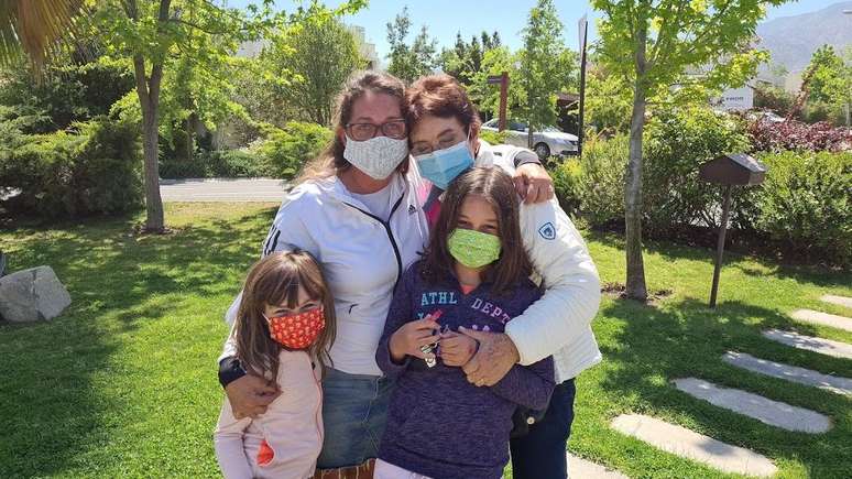 Fam&iacute;lia posa abra&ccedil;ada usando m&aacute;scaras