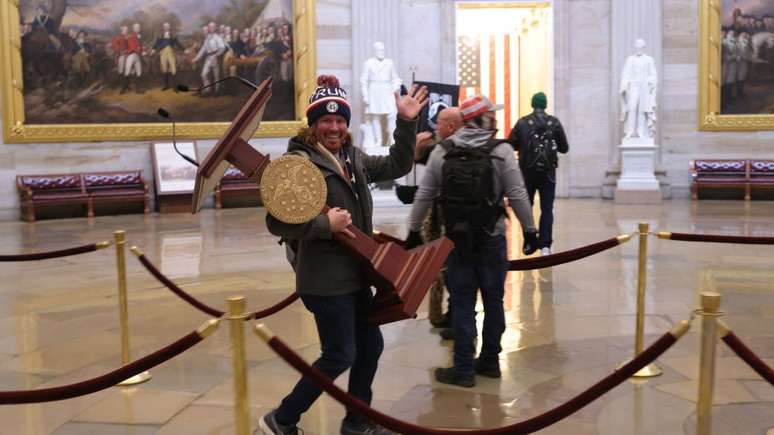 Outro manifestante é visto carregando um pedestal de uma sala no Capitólio dos EUA
