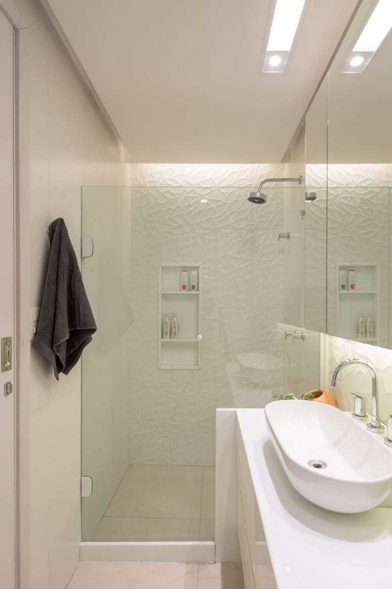 43. Bancada de granito branco, cuba oval de apoio e chuveiro cromado decoram o espa&ccedil;o. Projeto por Vita Arquitetura