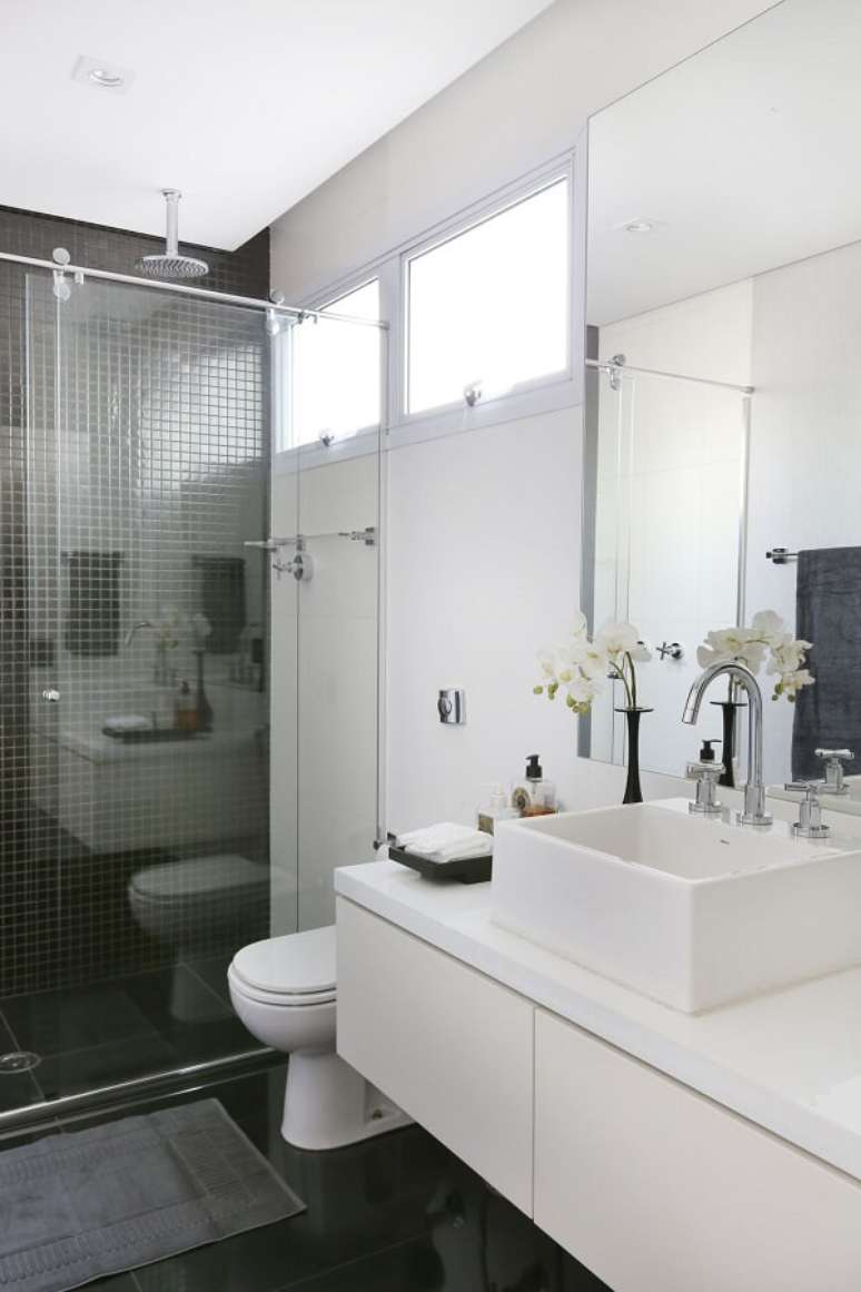 4. Banheiro branco com pastilhas pretas e chuveiro cromado trazem um ar sofisticado ao espaço. Projeto por Carolina Ouro