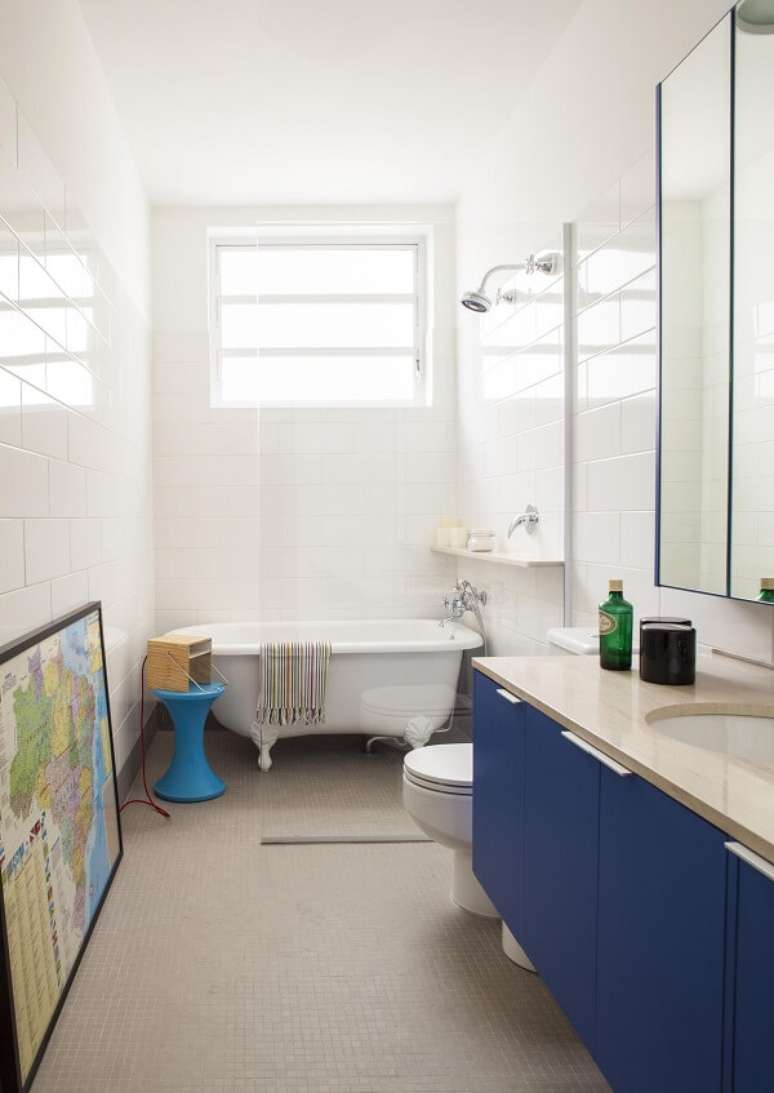 32. Banheiro com gabinete azul e chuveiro cromado. Projeto por Mauricio Arruda