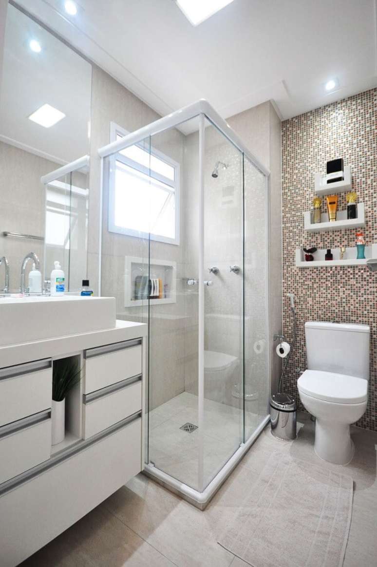 29. Banheiro com parede revestida com pastilhas e chuveiro cromado. Projeto por Condecorar Arquitetura e Interiores