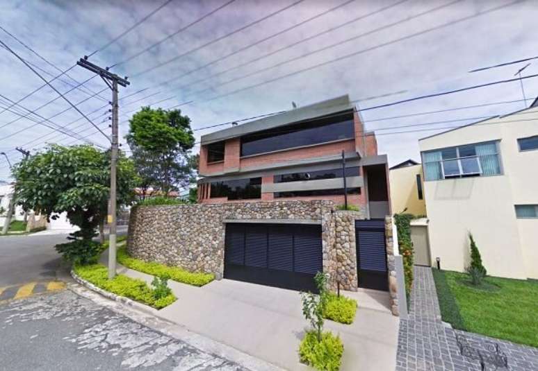 70. Port&atilde;o met&aacute;lico preto vazado e muros com pedras decorativas. Projeto por Douglas Piccolo Arquitetura e Planejamento Visual Ltda