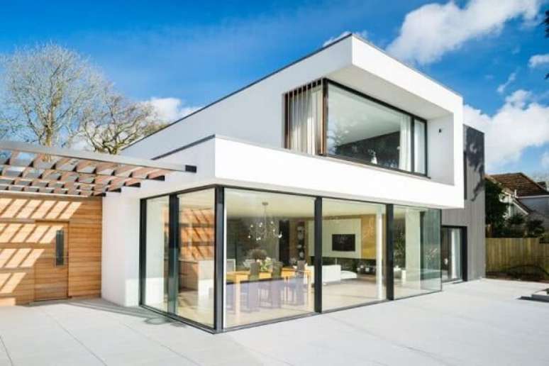 28. Casa sobrado simples com fachada branca, painéis de vidro e janelas fixadas com estrutura metálica preta. Fonte: Pinterest