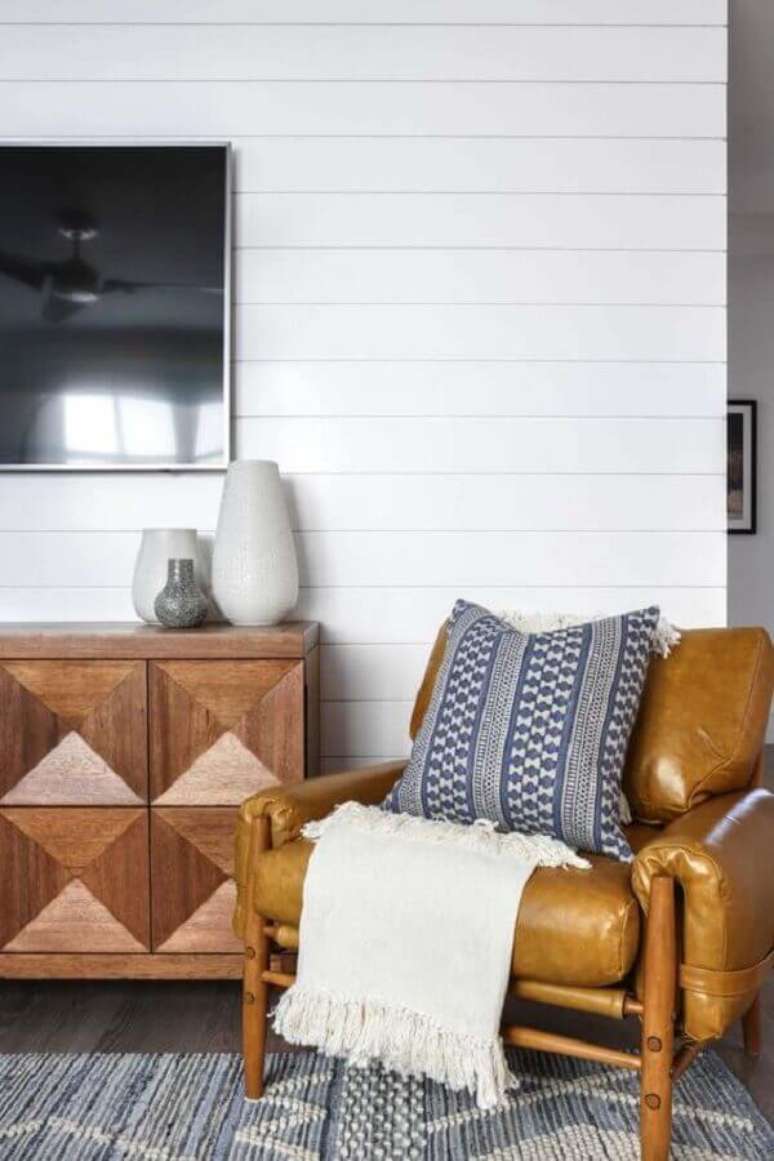 49. Poltrona de couro e madeira para sala de TV decorada com manta bege &ndash; Foto: One Kindesign