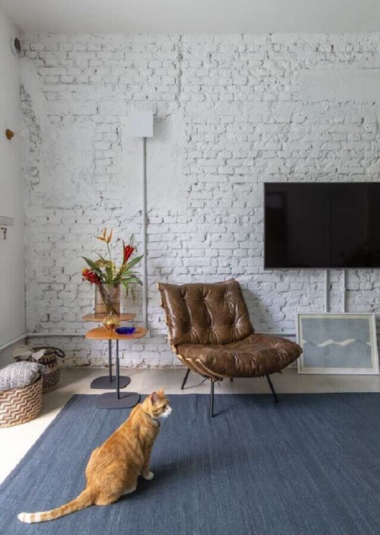58. Poltrona de couro marrom escuro para sala de TV rústica decorada com parede de tijolinho branca – Foto: INÁ Arquitetura