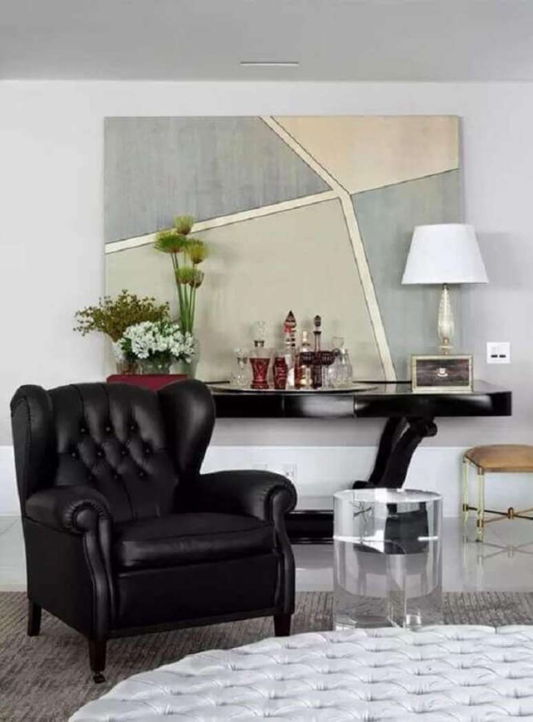 3. Sala sofisticada decorada com quadro grande e poltrona de couro preta antiga – Foto: Pinterest