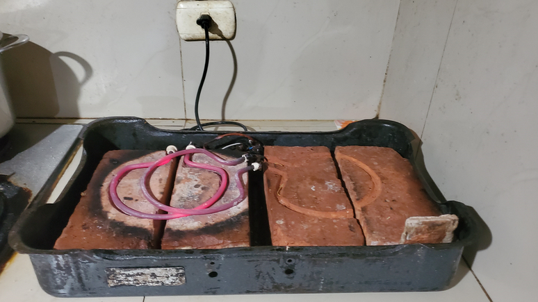 Fogão elétrico improvisado com tijolos e instrumentos de aquecimento antigos