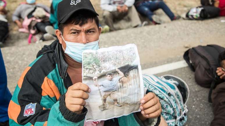 Wilmer, um hondurenho da caravana de migrantes que atravessa a Guatemala, mostra uma foto de sua casa destruída pela tempestade Eta, motivo pelo qual decidiu ir para os EUA