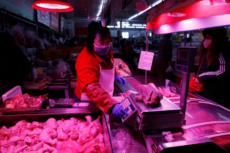 Vendedora pesa frango em mercado de Pequim. REUTERS/Tingshu Wang