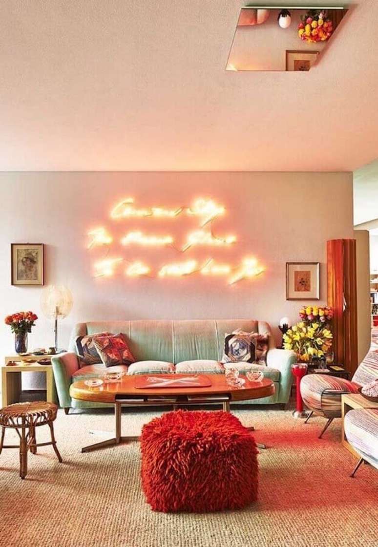 30. Decoração com puff colorido para sala com luminária neon – Foto: Decorholic