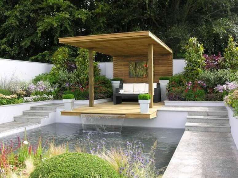 23- A sa&iacute;da de &aacute;gua da cascata para piscina &eacute; sob o deck de madeira. Fonte: Tudo &eacute; Dimais