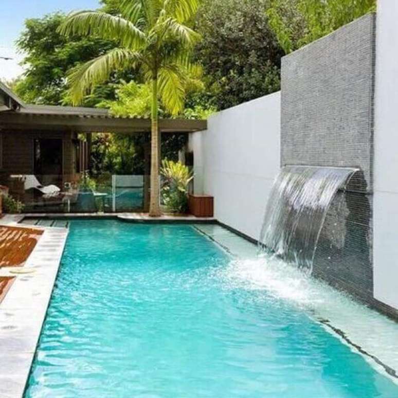 53- A parede com pastilhas cinza tem cascata para piscina embutida. Fonte: Cooperativa das Piscinas