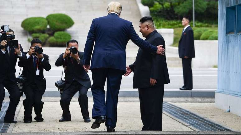 Trump caminha para o lado norte da linha de demarcação militar que divide a Coréia do Norte e a Coréia do Sul em junho de 2019 ao lado do líder norte-coreano Kim Jong-un