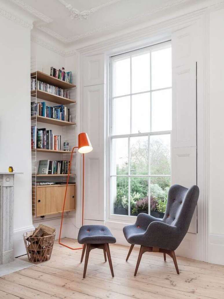 13. Cantinho de leitura simples todo branco decorado com luminária laranja e poltrona com puff para leitura – Foto: Archilovers