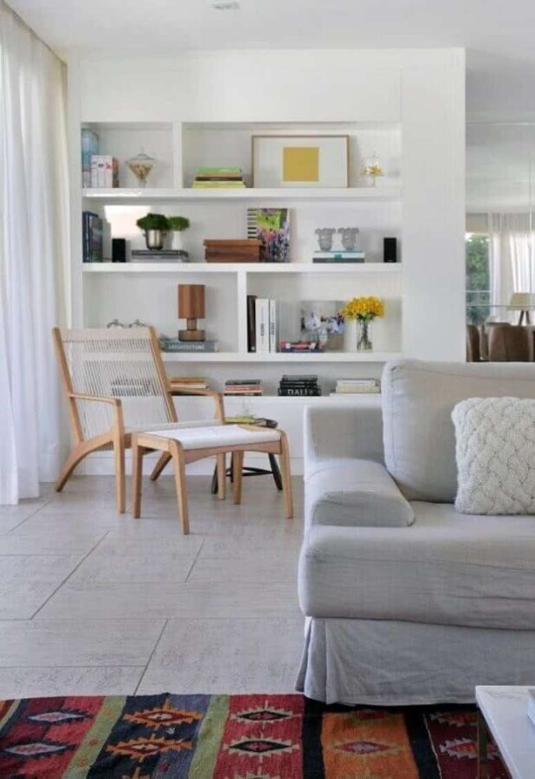 18. Decoração de sala branca com sofá cinza e poltrona para leitura com puff – Foto: Pinterest
