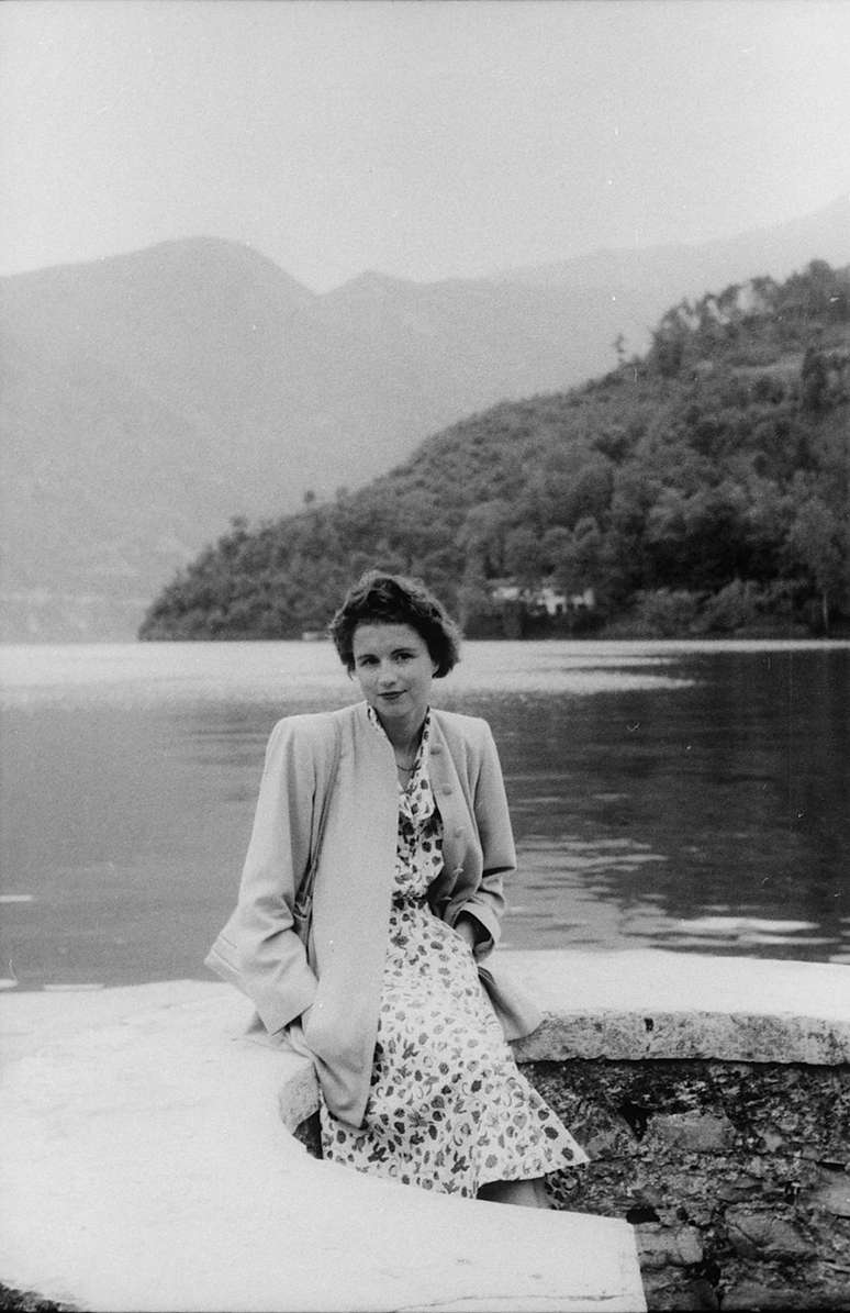 Mulher posa ao lado de lago
