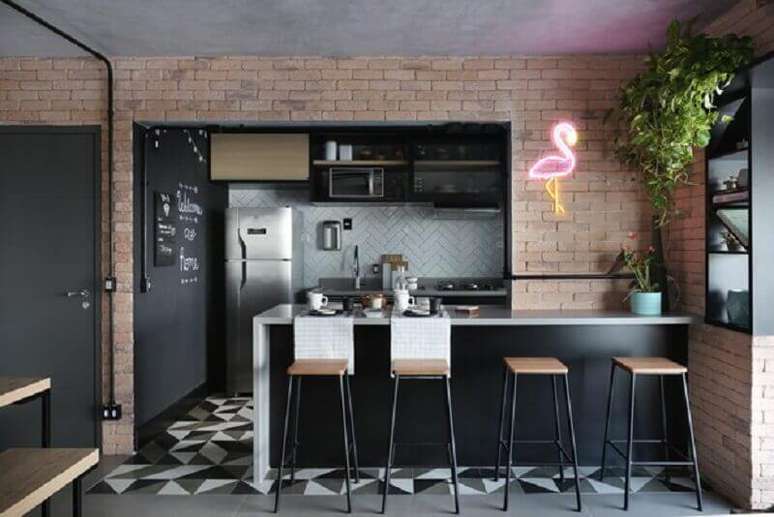 9. Decoração de cozinha americana estilo industrial com parede de tijolinho e luminária neon em formato de flamingo – Foto: Apartment Therapy