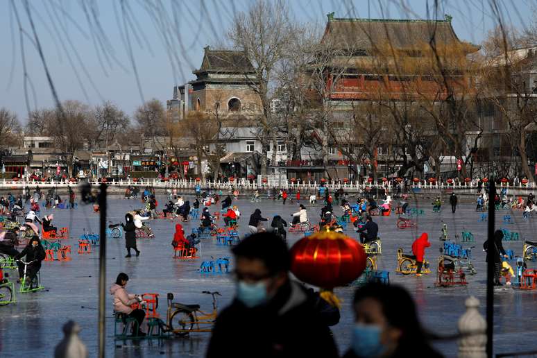 Pessoas usam máscaras em um lago congelado em Pequim em meio ao surto de Covid-19. REUTERS/Tingshu Wang