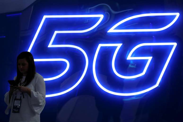 Mulher observa seu smartphone pr&oacute;xima a um an&uacute;ncio da tecnologia 5G. 25/2/2019. REUTERS/Sergio Perez