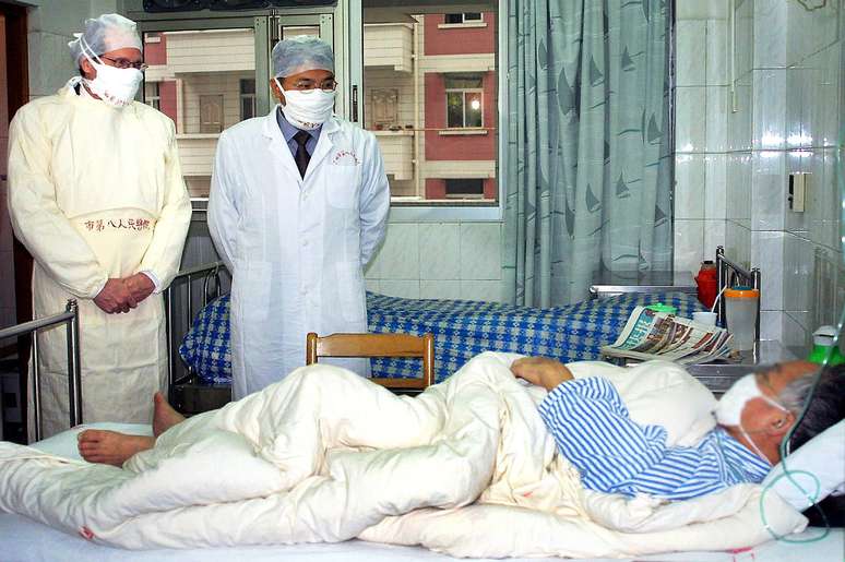 Robert Maguire, da OMS, e médico chinês visitam paciente com Sars em Guangzhou em abril de 2003: houve críticas em relação à transparência das autoridades chinesas durante a epidemia