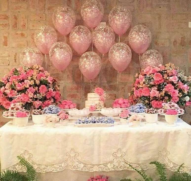 68. Decoração simples para festa de aniversário de 15 anos com bexigas cor de rosa com glitter dourado e arranjos de flores na mesa – Foto: Pinterest