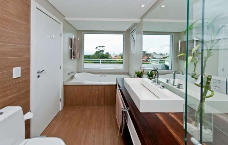 45. Bancada de madeira extensa acomoda uma linda e cuba de apoio para banheiro branca. Projeto por Juliana Pippi