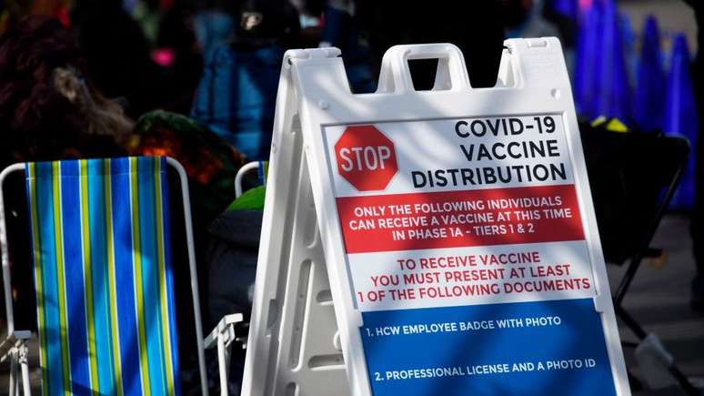 Cartaz em inglês aponta requisitos para a aplicação de vacina, como identidade com foto e licença profissional