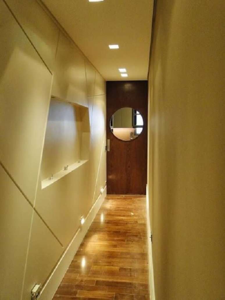 24. Além da luminária para corredor pequeno no teto é possível perceber a presença de luminária de parede para corredor. Projeto por Debora Nanni