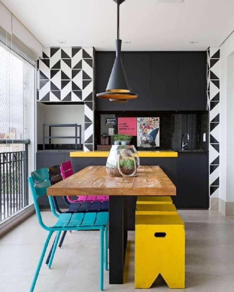 8. Cadeiras coloridas para decoração de varanda gourmet com armários pretos planejados – Foto: Dicas de Mulher