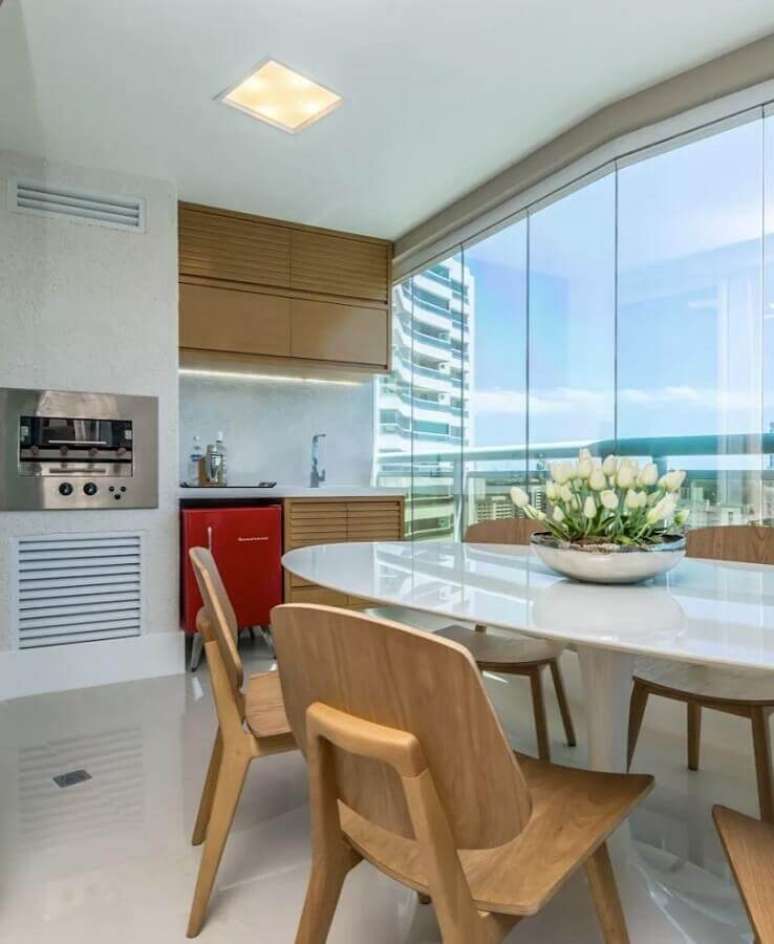 26. Cadeiras e arm&aacute;rios de madeira para varanda de apartamento decorada toda branca com churrasqueira &ndash; Foto: Homify