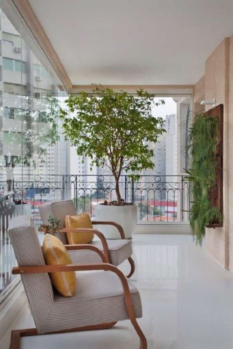 36. Jardim vertical para decoração de varanda de apartamento com poltronas de madeira e vaso de planta grande – Foto: Casa de Valentina