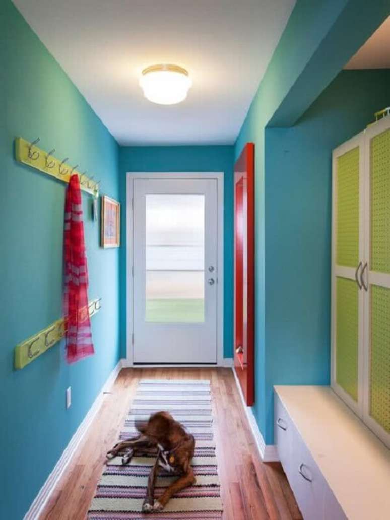 39. Modelo de luminária para corredor interno com parede azul e decoração vermelha e verde. Fonte: Pinterest