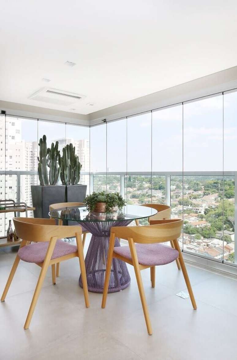 61. Mesa redonda de vidro para decoração de varanda de apartamento com cadeiras de madeira – Foto: Karen Pisacane