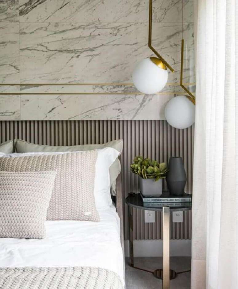 43. Mesa de canto redonda para quarto sofisticado decorado com luminária moderna e parede de mármore – Foto: Behance