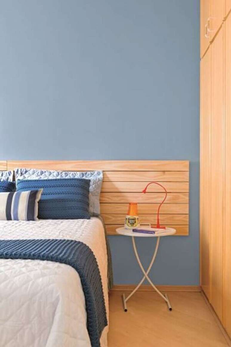 44. Mesa de canto pequena para quarto azul decorado com cabeceira de madeira – Foto: Pinterest